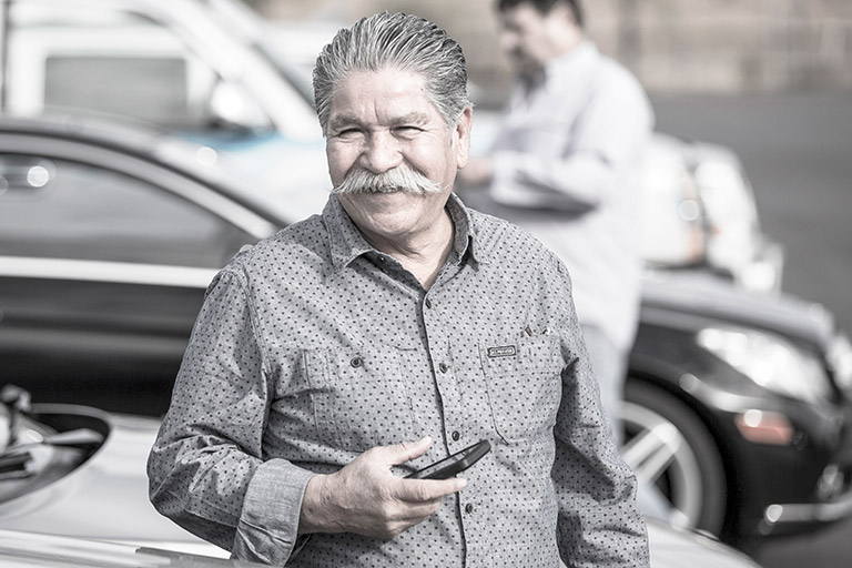 Man standing in front of car with phone